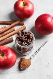 Fresh apples with cinnamon sticks and powder on table