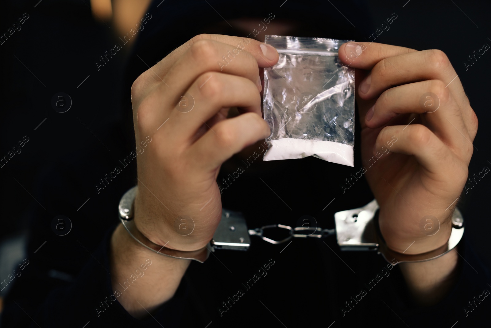 Photo of Man detained in handcuffs holding bag with drug, closeup. Criminal law