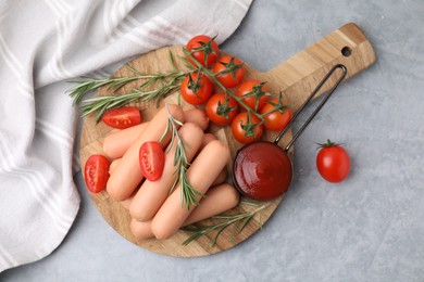 Delicious boiled sausages, tomato sauce, tomatoes and rosemary on gray table, top view