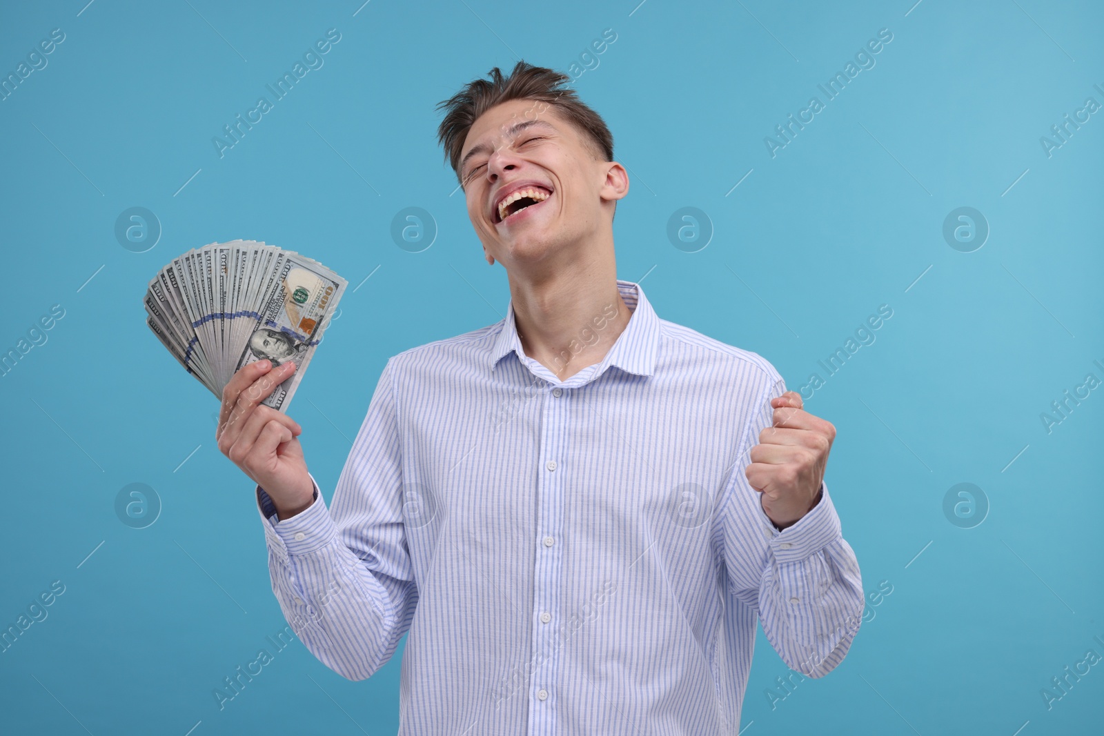 Photo of Happy man with dollar banknotes on light blue background