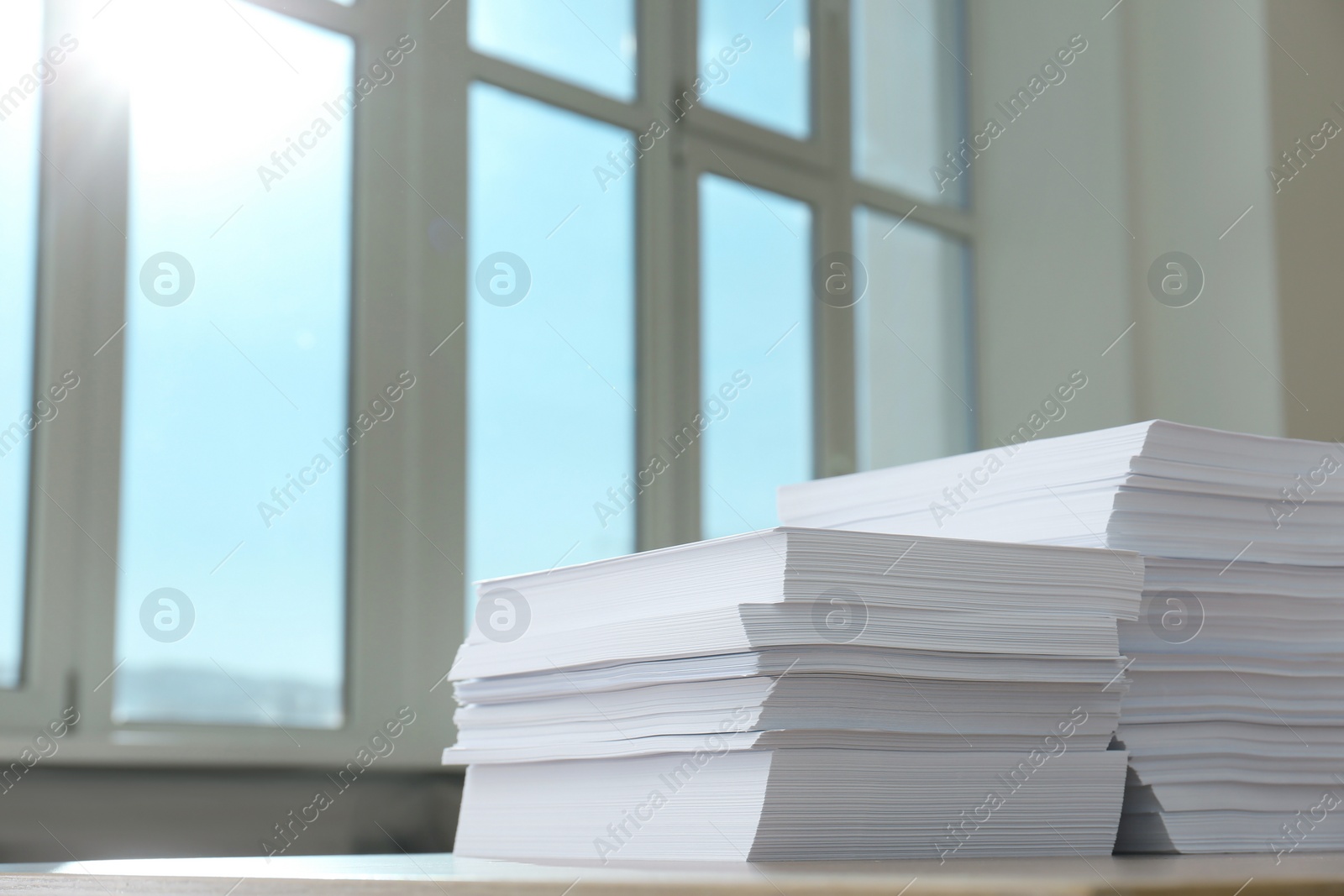 Photo of Stacks of paper sheets on wooden table indoors. Space for text