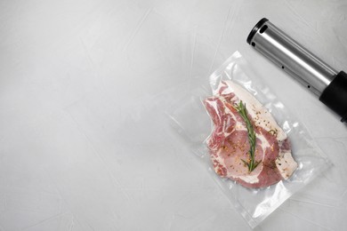 Photo of Vacuum packing sealer with plastic bag of meat on light grey table, top view. Space for text