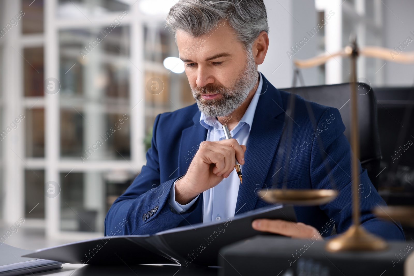 Photo of Portrait of serious lawyer at table in office