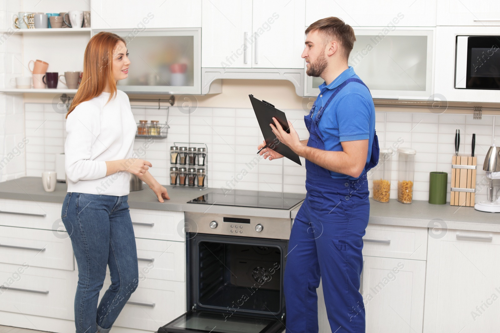 Photo of Housewife with repairman near modern oven in kitchen