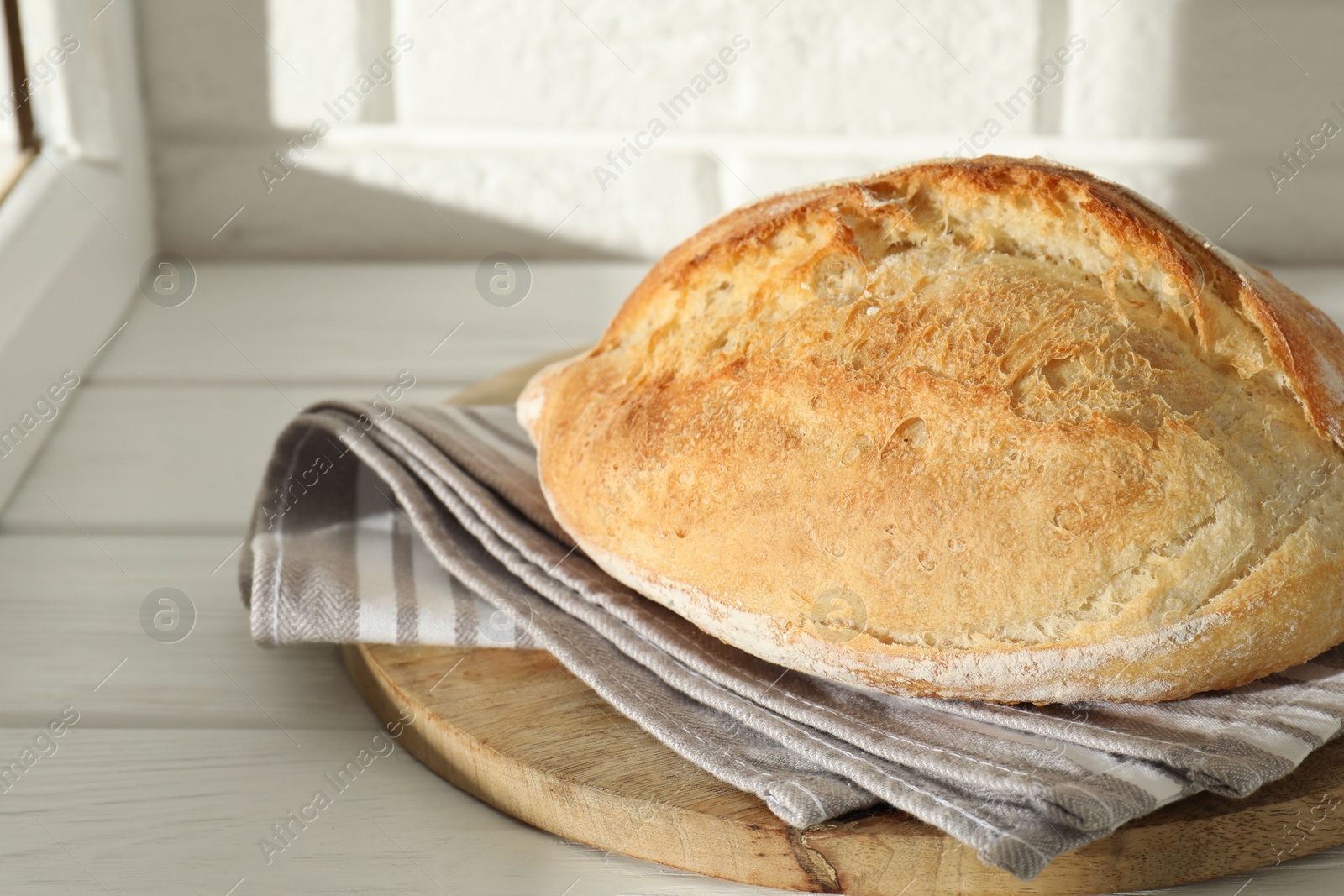 Photo of Freshly baked sourdough bread on white wooden table indoors. Space for text