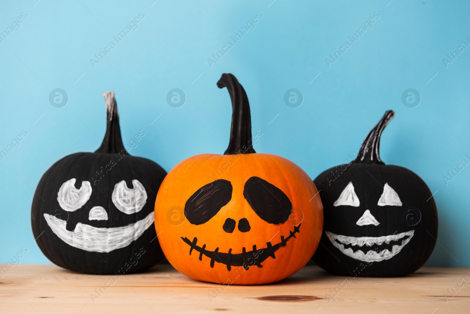 Photo of Halloween celebration. Pumpkins with spooky drawn faces on wooden table