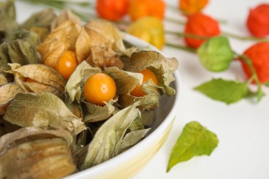 Photo of Ripe physalis fruits with dry husk on white table, closeup