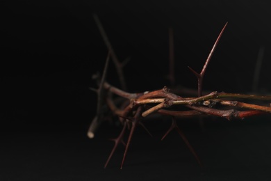 Photo of Crown of thorns on dark background, closeup with space for text. Easter attribute