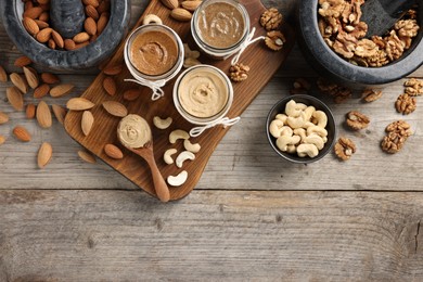 Photo of Making nut butters from different nuts. Flat lay composition with space for text on wooden table