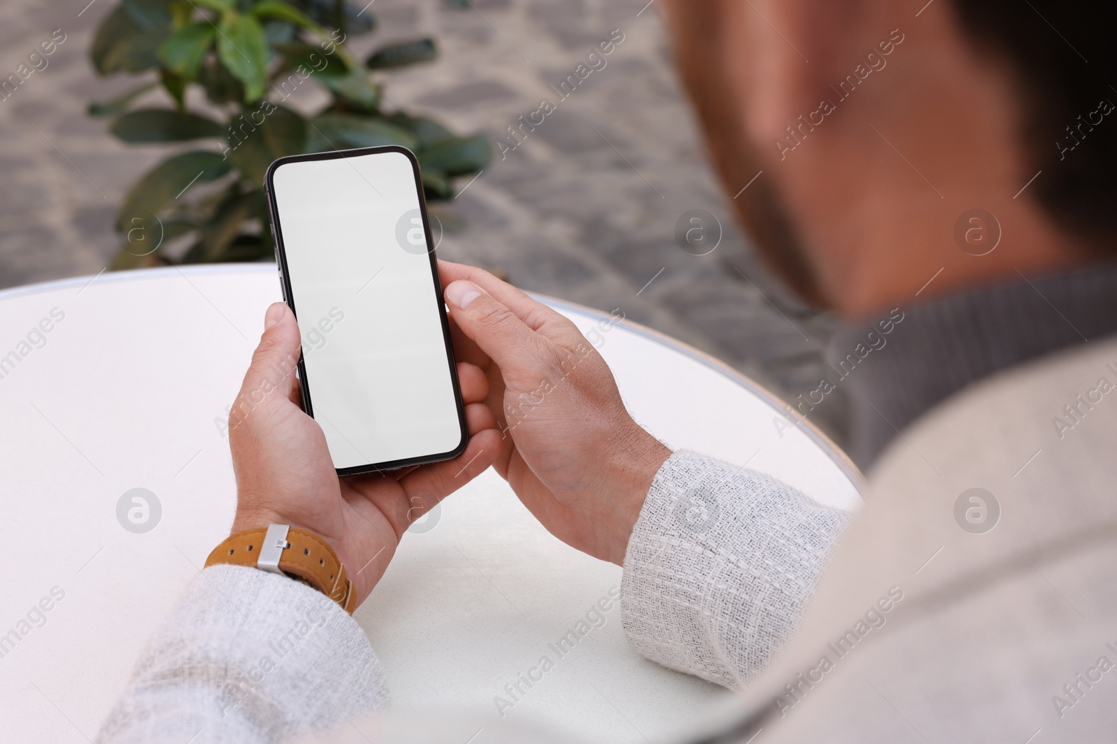 Photo of Man using mobile phone at white table, closeup. Space for text