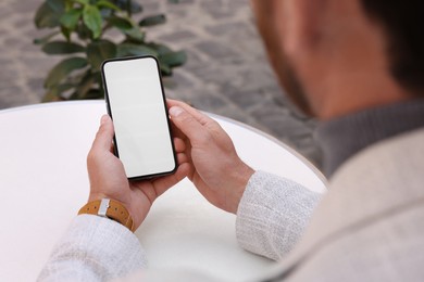 Man using mobile phone at white table, closeup. Space for text