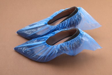 Photo of High heels in shoe covers on brown background, closeup