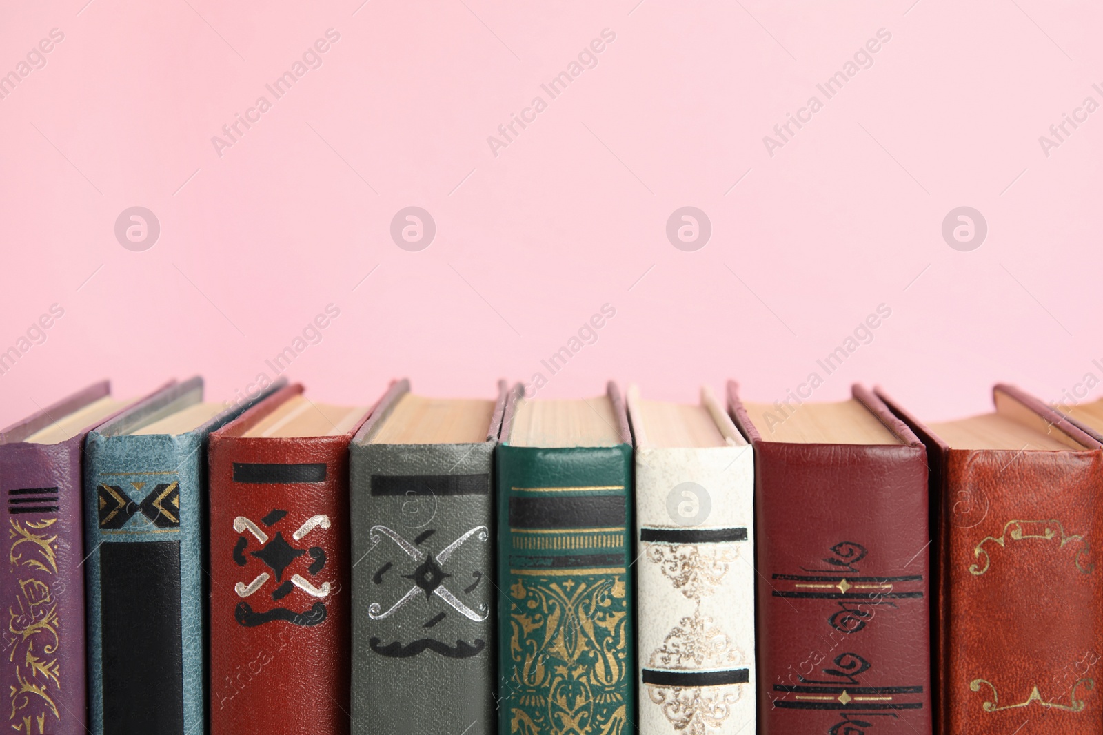 Photo of Collection of old books on pink background, space for text