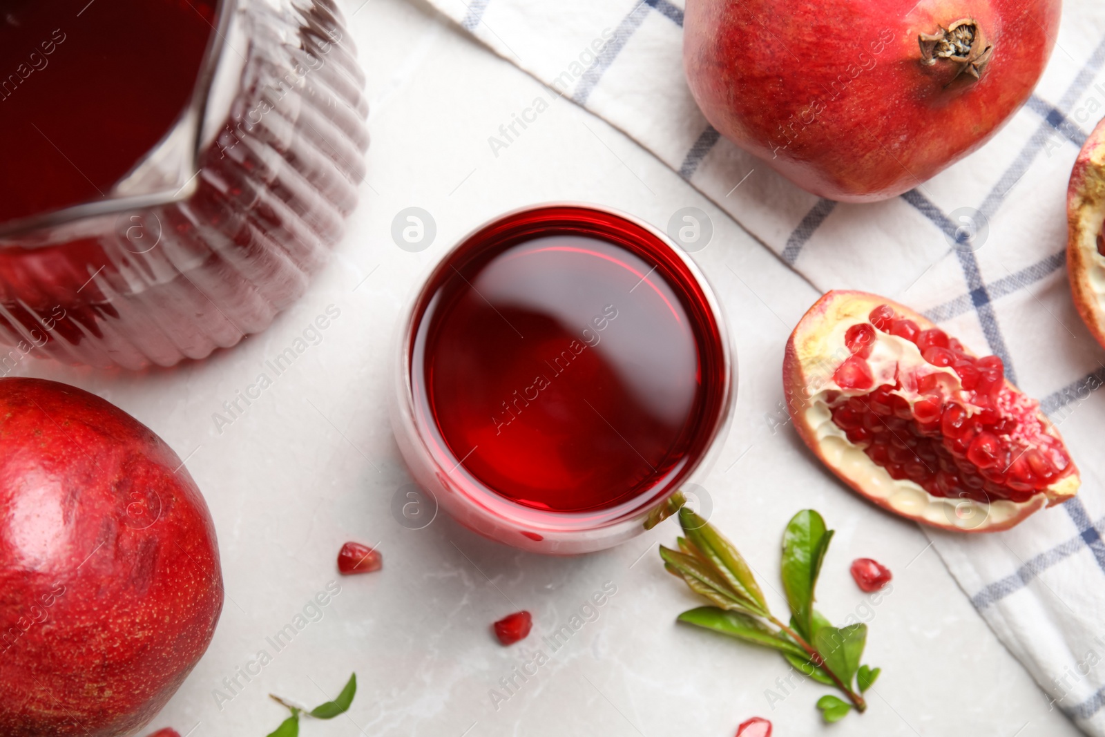 Photo of Glass of pomegranate juice and fresh fruits on light marble table, flat lay