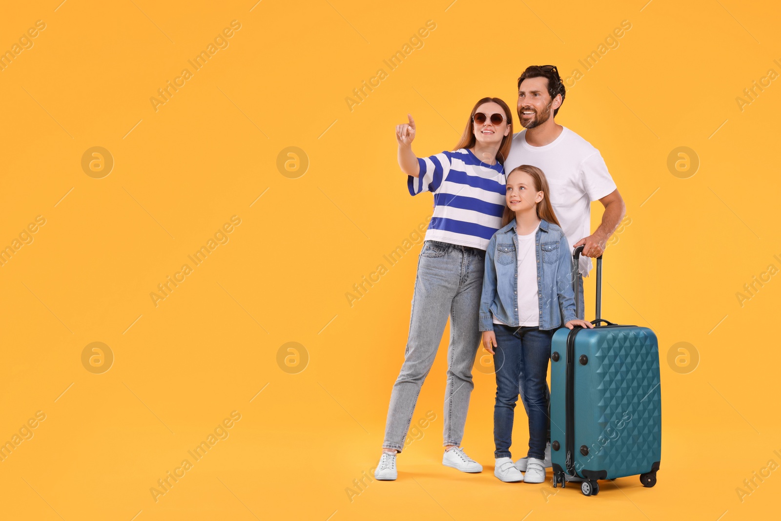 Photo of Happy family with green suitcase on orange background, space for text