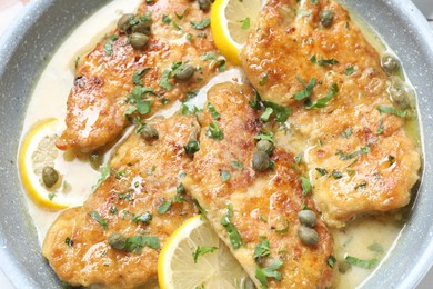 Delicious chicken piccata with lemons and herbs in pan, closeup