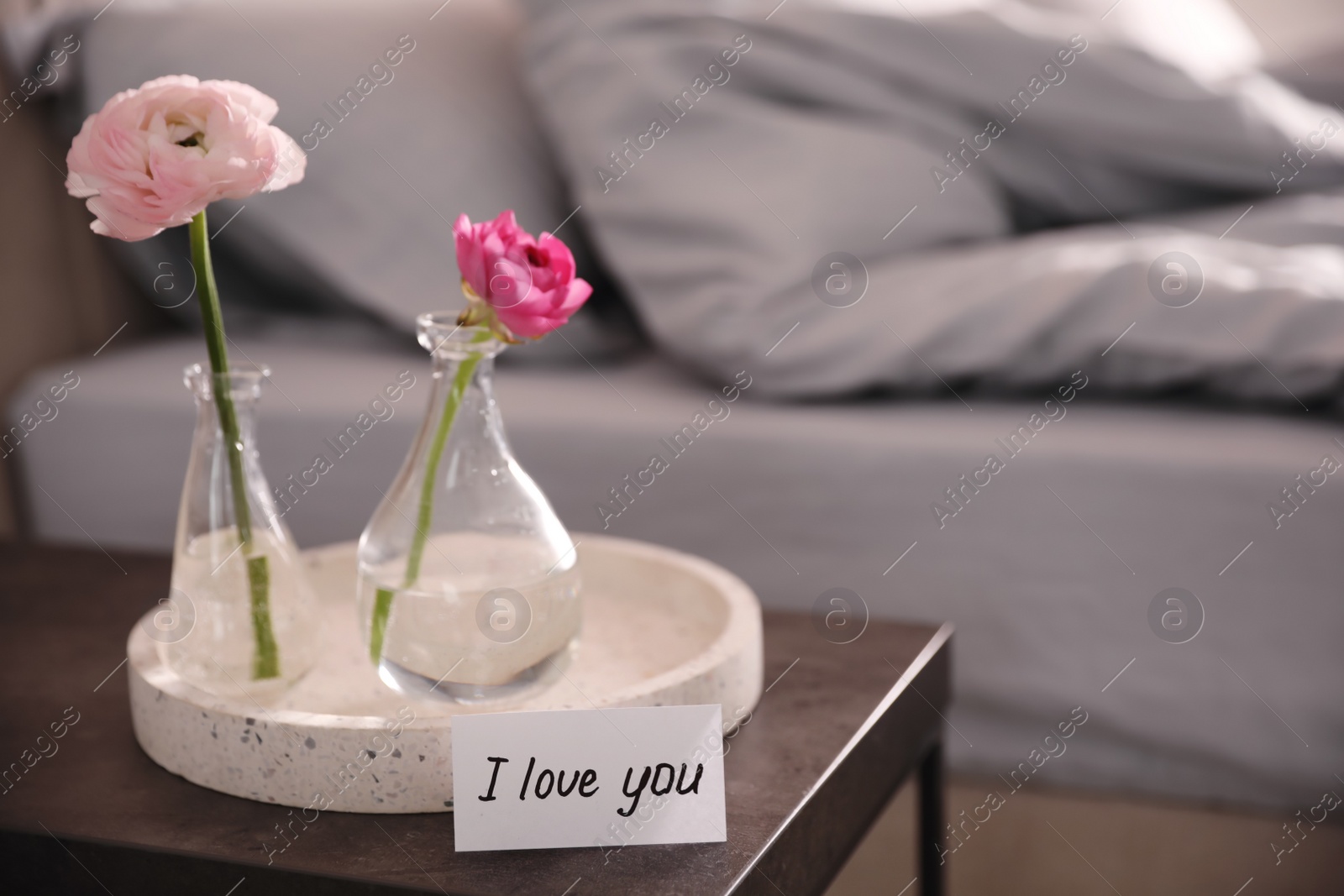 Photo of Note saying I Love You near tray with flowers on bedside table in room