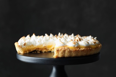 Stand with delicious lemon meringue pie on black background