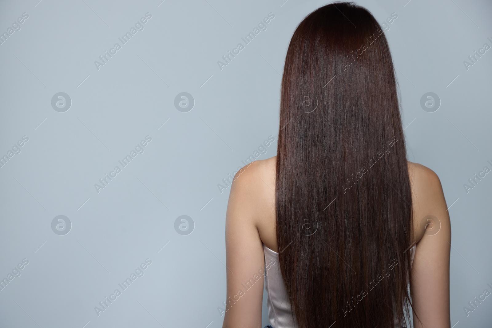 Photo of Young woman with healthy strong hair on light gray background, back view. Space for text