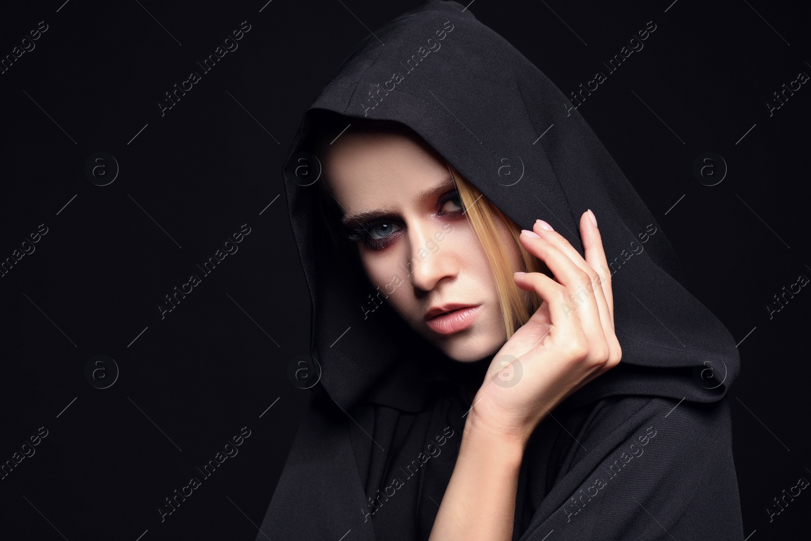 Photo of Witch in black mantle on dark background. Scary fantasy character