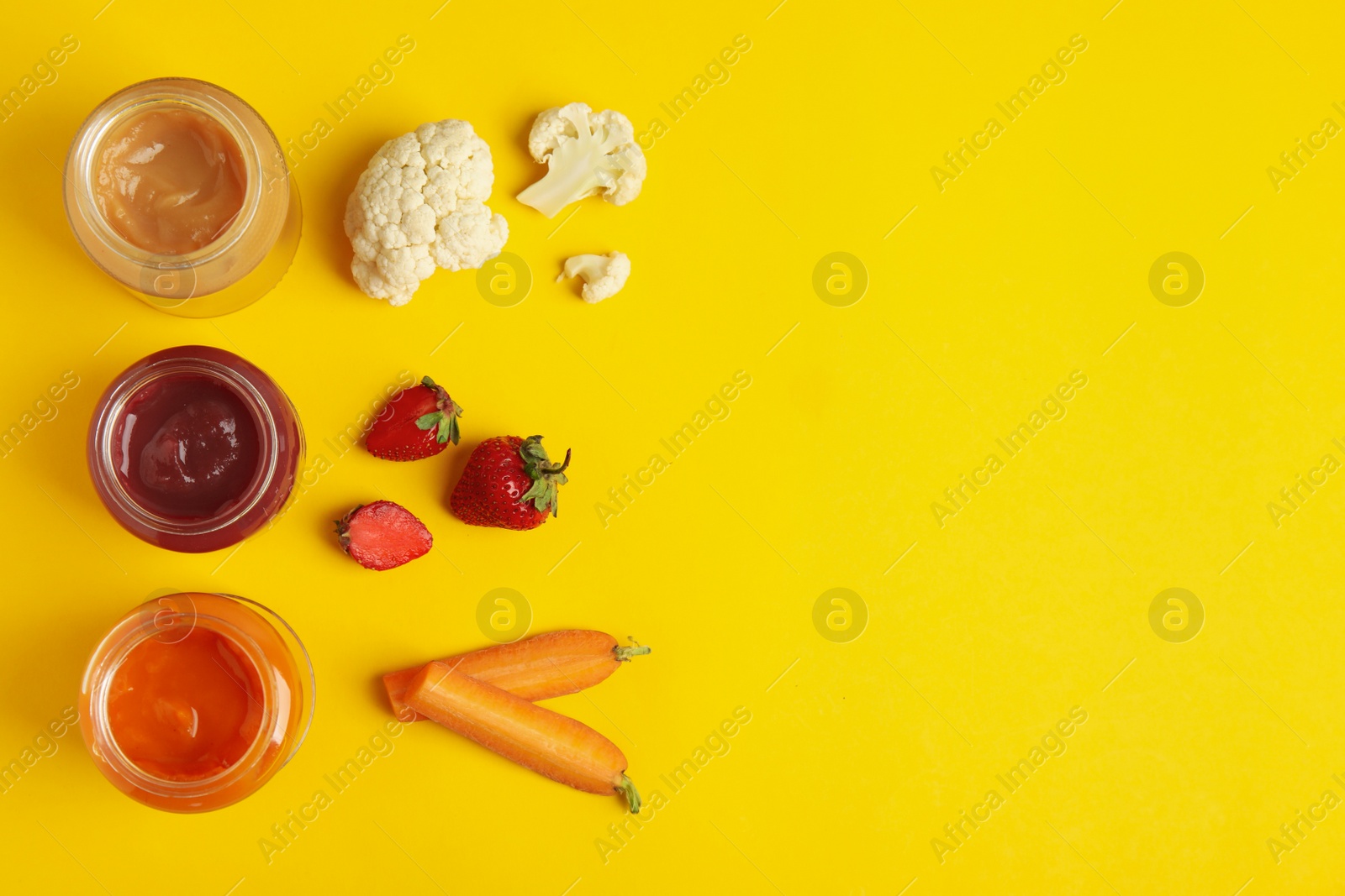 Photo of Healthy baby food in jars and fresh ingredients on yellow background, flat lay. Space for text