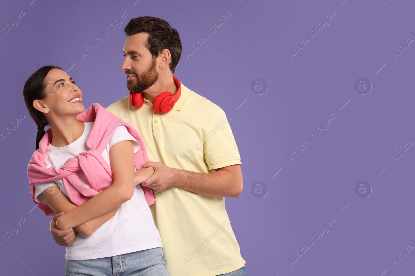 Photo of Happy couple dancing together on violet background, space for text