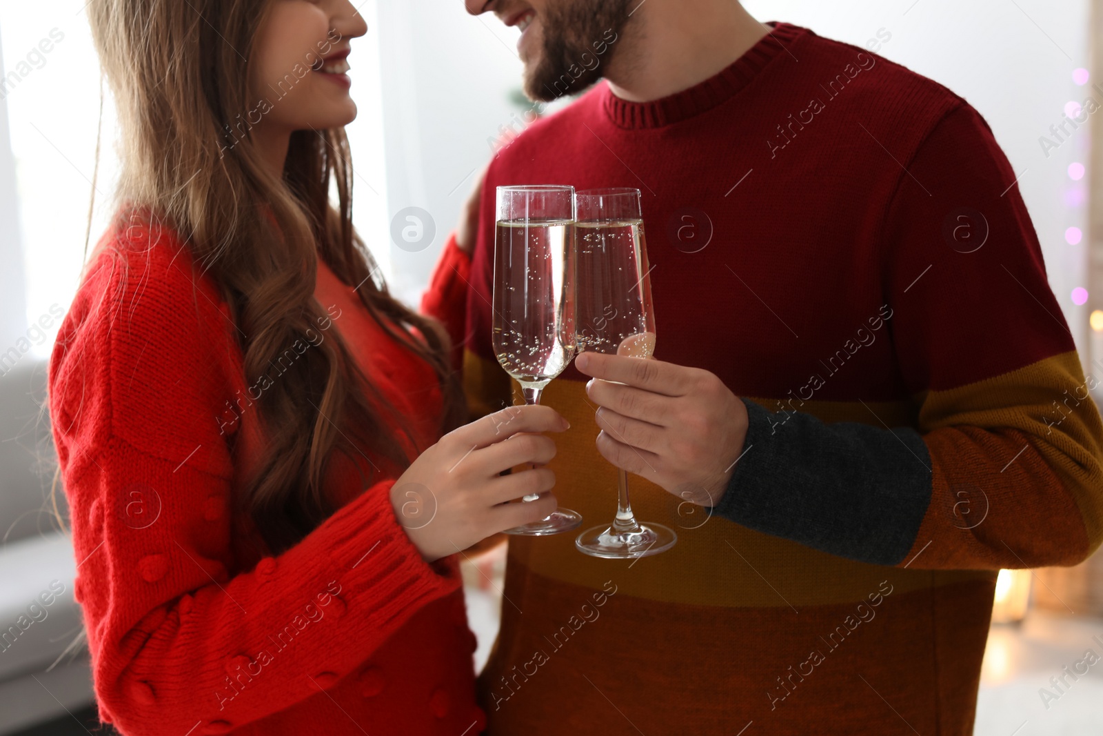 Photo of Happy young couple with glasses of champagne celebrating Christmas at home