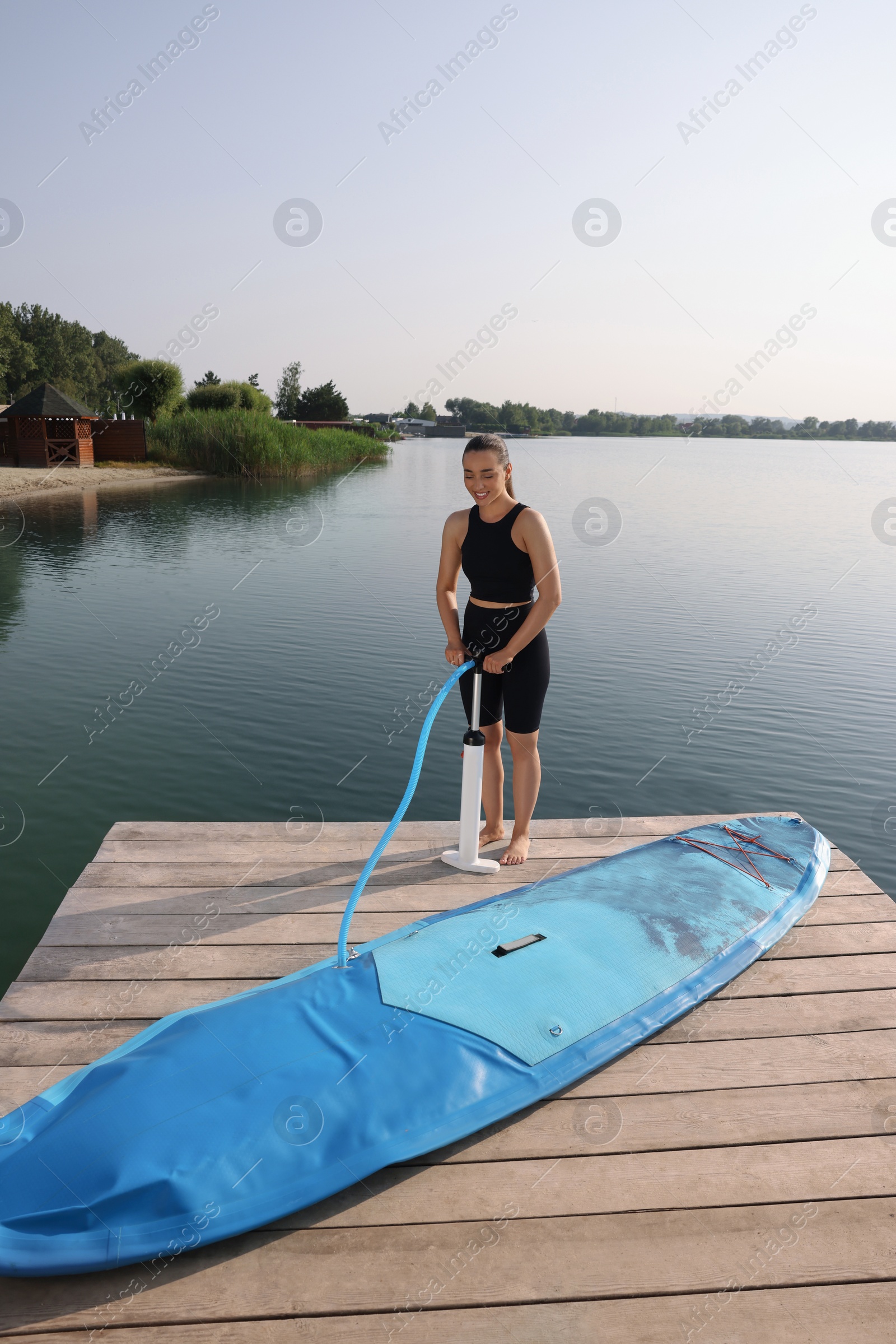 Photo of Woman pumping up SUP board on pier