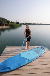 Woman pumping up SUP board on pier