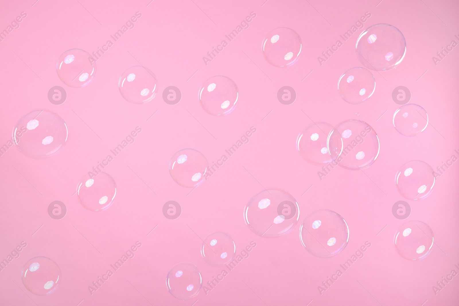 Photo of Many beautiful soap bubbles on pink background