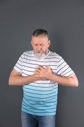 Photo of Mature man having heart attack on gray background