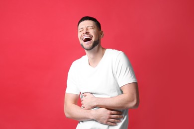 Handsome man laughing on red background. Funny joke