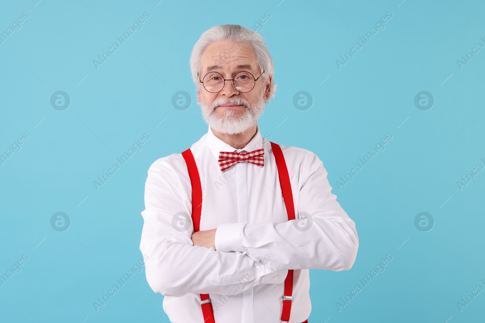 Photo of Portrait of stylish grandpa with glasses and bowtie on light blue background