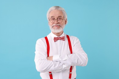 Portrait of stylish grandpa with glasses and bowtie on light blue background