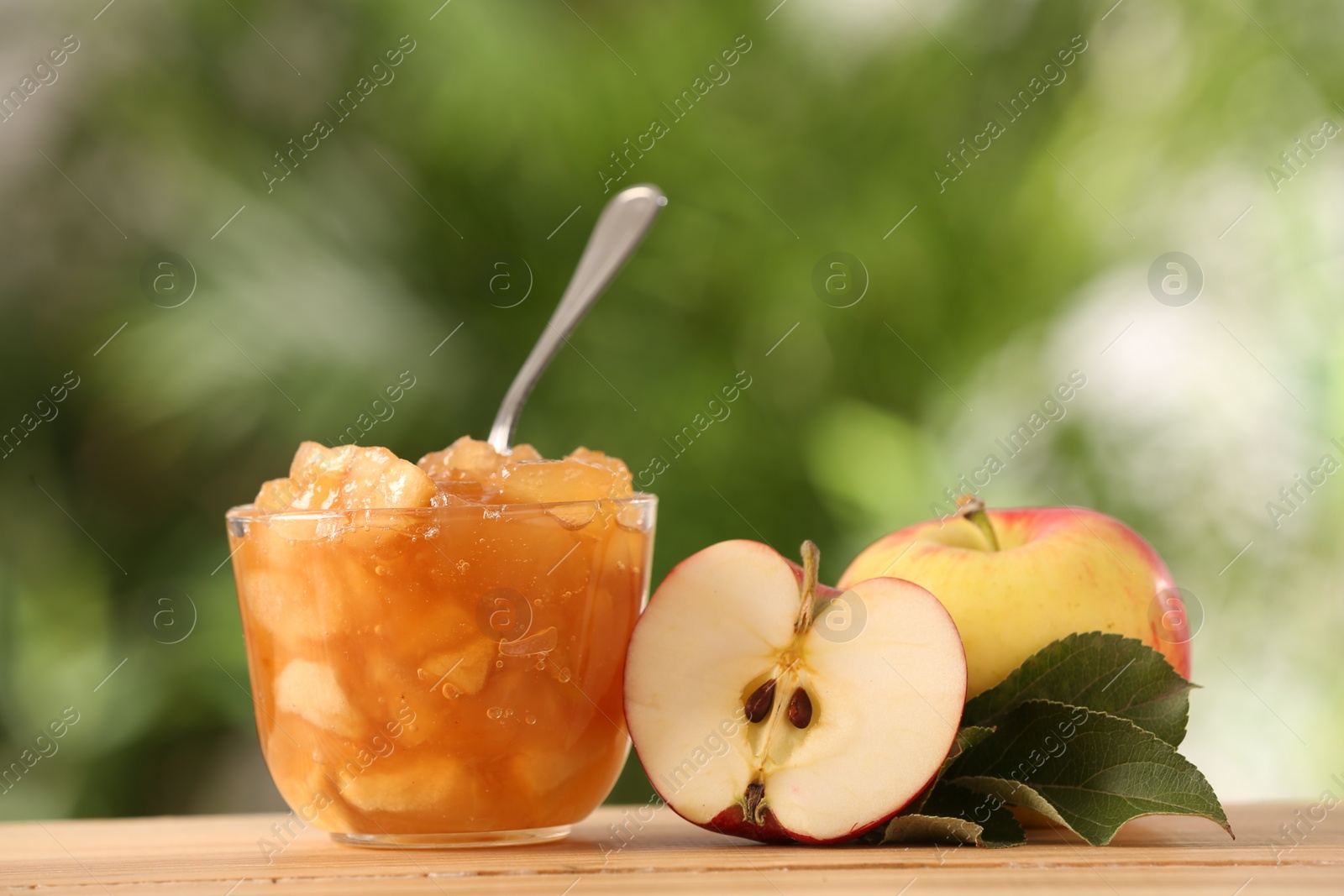 Photo of Delicious apple jam and fresh fruits on wooden table