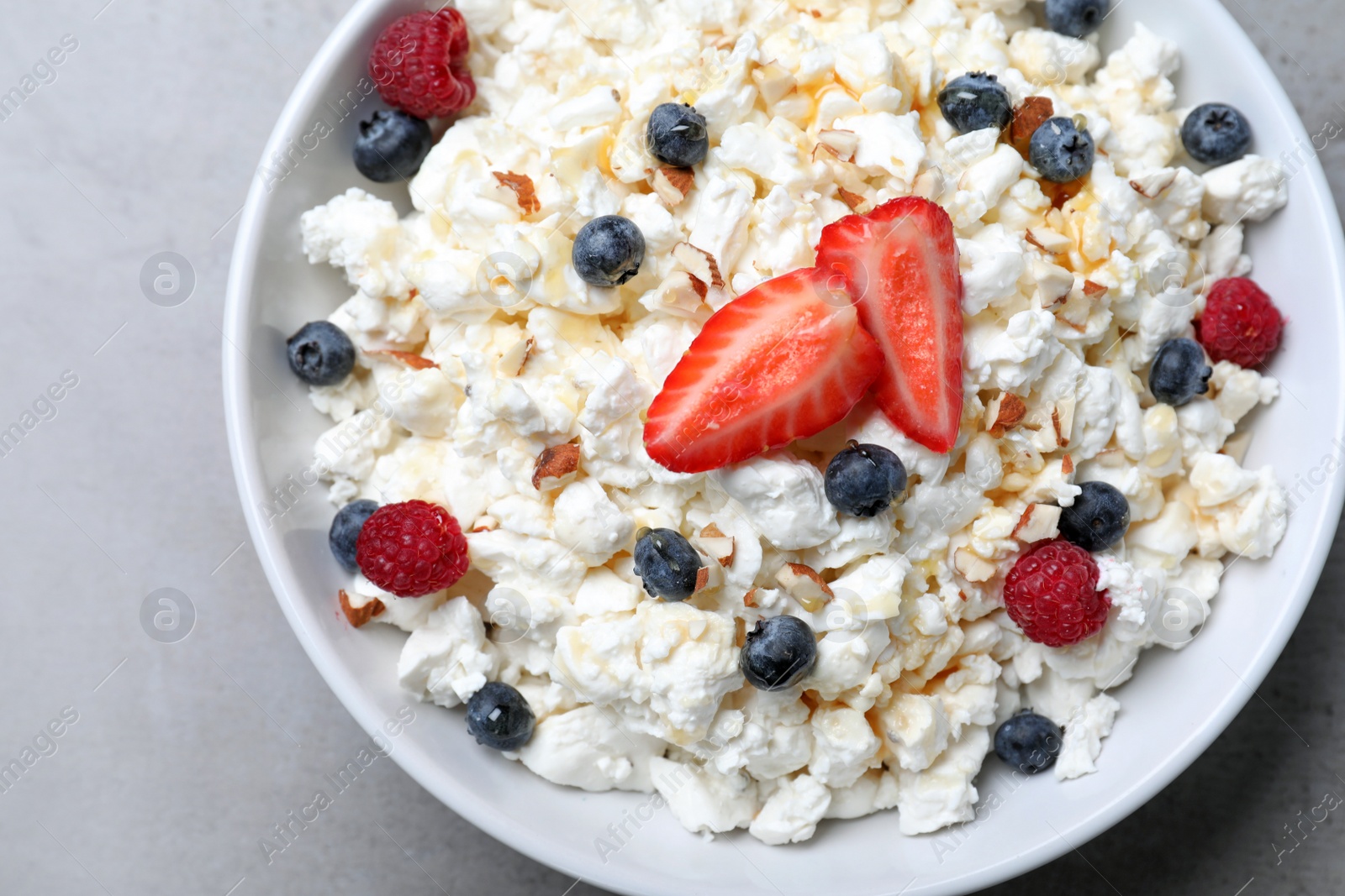 Photo of Delicious cottage cheese with fresh berries served for breakfast on light grey table, top view