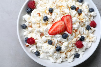 Delicious cottage cheese with fresh berries served for breakfast on light grey table, top view