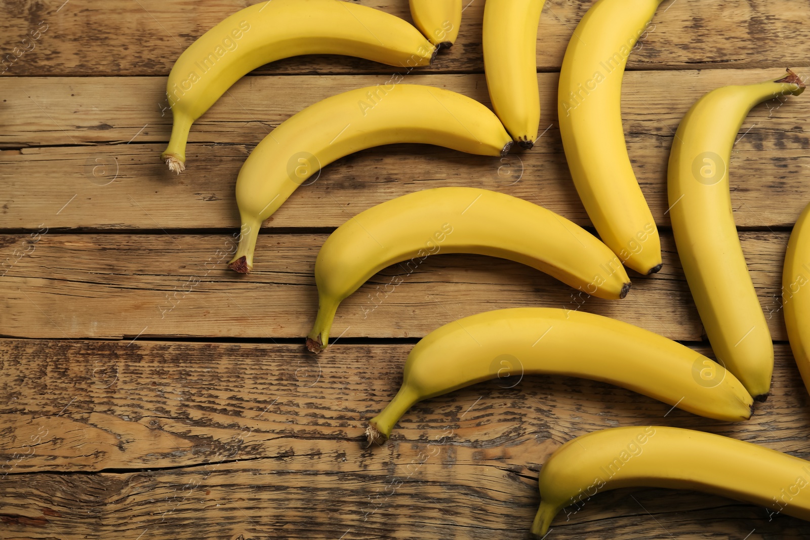 Photo of Ripe sweet yellow bananas on wooden table, flat lay