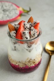 Glass jar of granola with pitahaya, yogurt and strawberries on white table