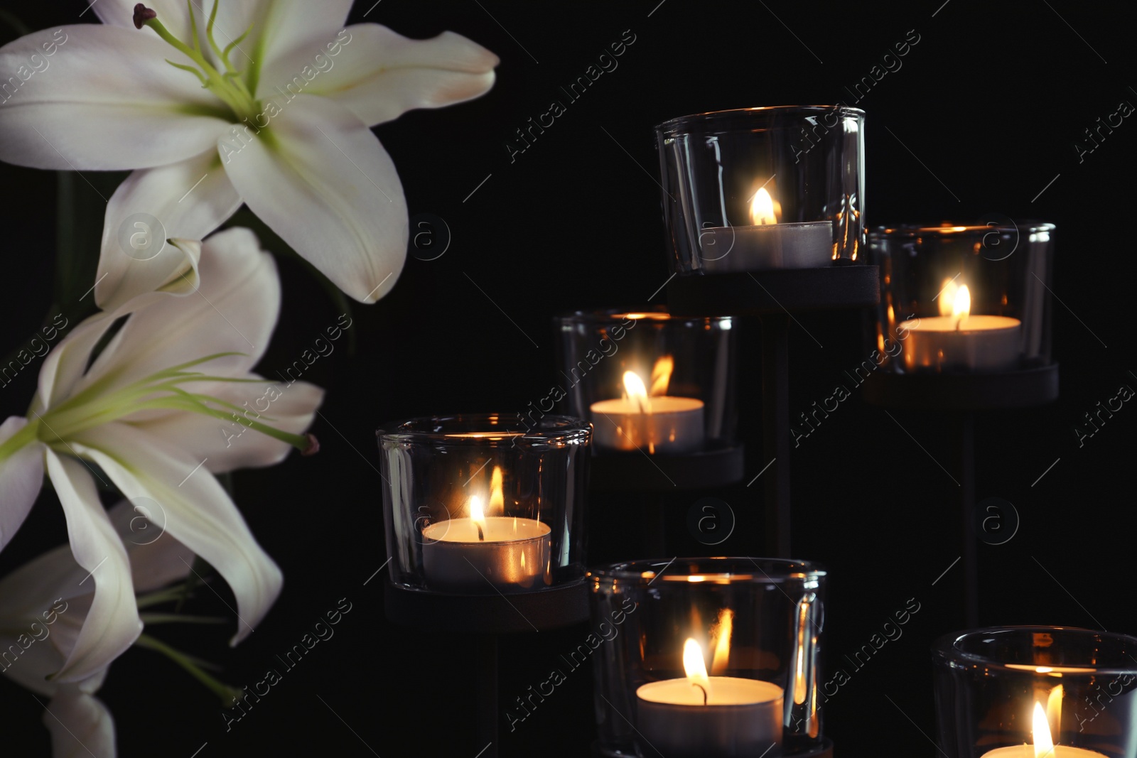 Photo of Burning candles and flowers on dark background. Funeral symbol