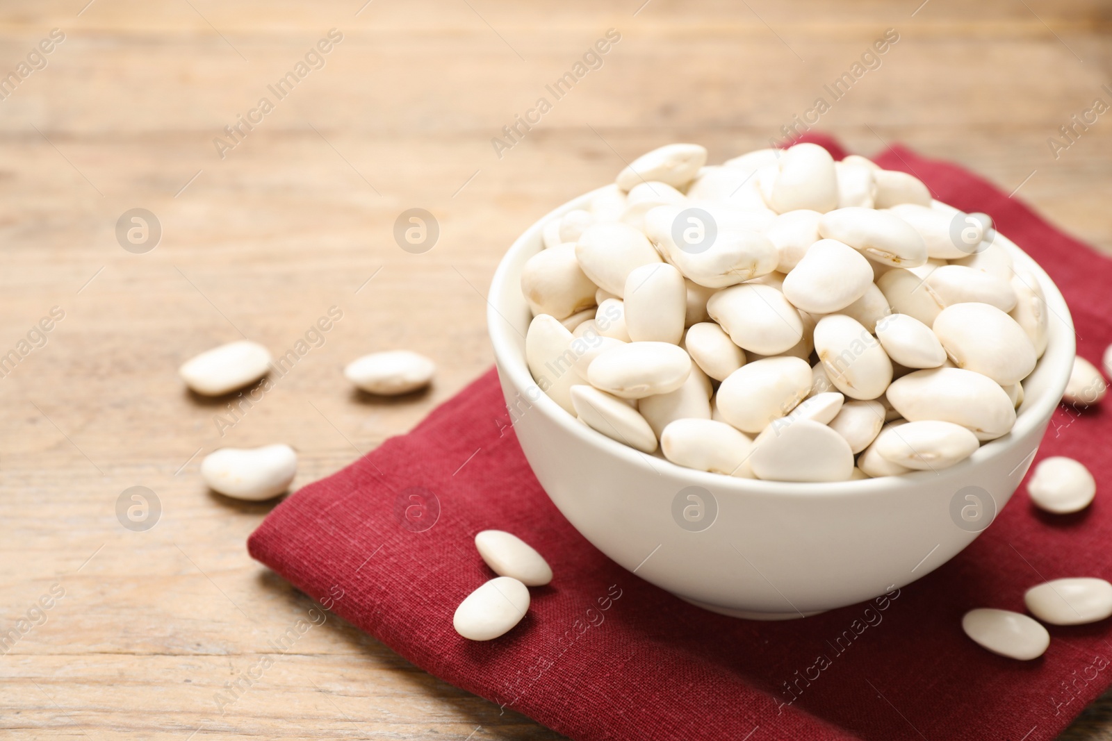 Photo of Raw white beans on wooden table, closeup. Space for text