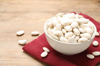Raw white beans on wooden table, closeup. Space for text