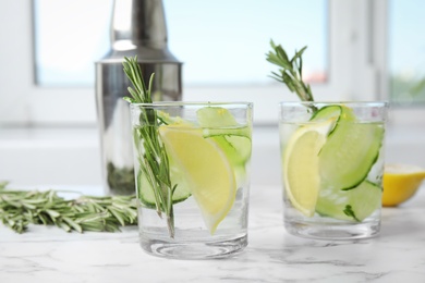 Photo of Refreshing lemon cocktail with rosemary on marble table