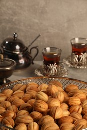 Photo of Delicious walnut shaped cookies and glasses of tea on grey table, closeup. Tasty pastry with filling carrying nostalgic home atmosphere