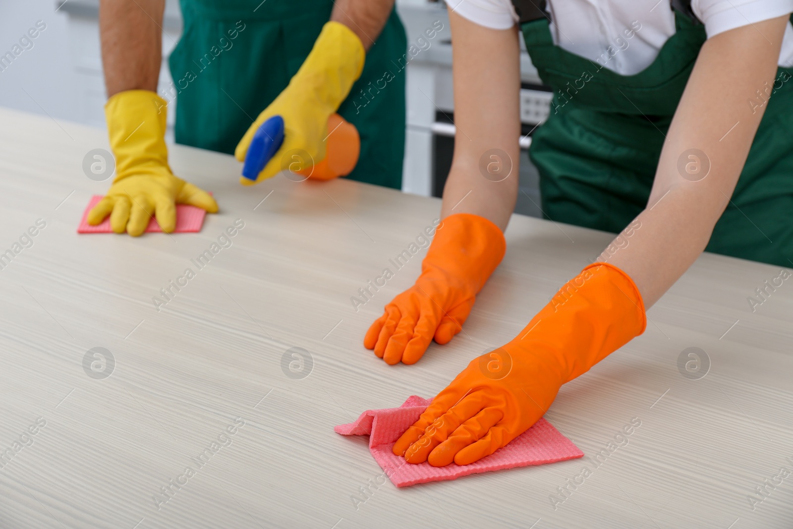 Photo of Team of janitors cleaning table in kitchen, closeup