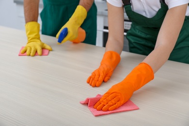 Photo of Team of janitors cleaning table in kitchen, closeup