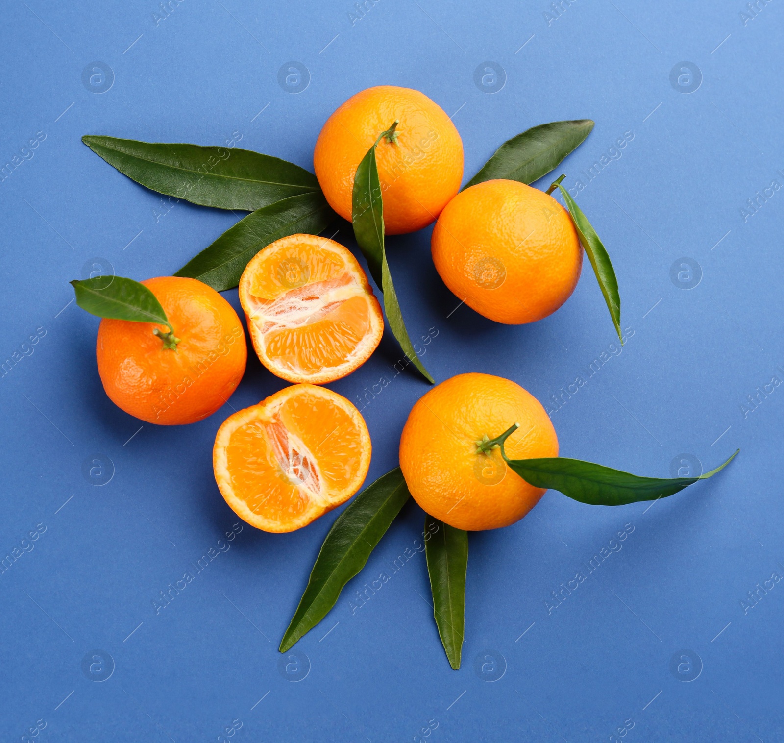 Photo of Fresh tangerines with green leaves on blue background, flat lay