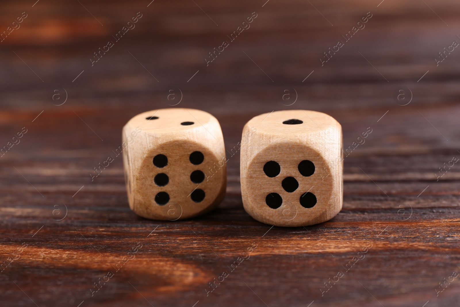 Photo of Two game dices on wooden table, closeup
