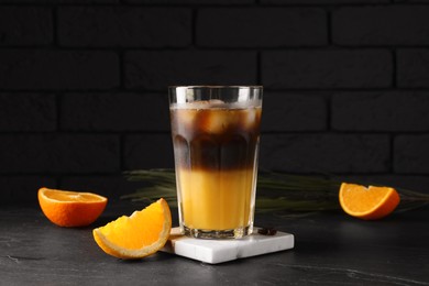 Photo of Tasty refreshing drink with coffee and orange juice on grey table against dark background