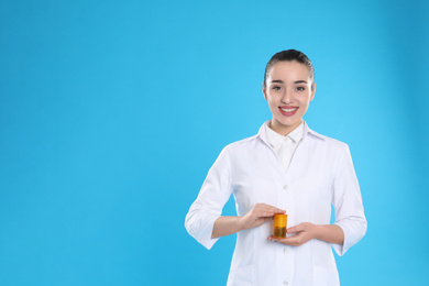 Photo of Professional pharmacist with pills on light blue background. Space for text